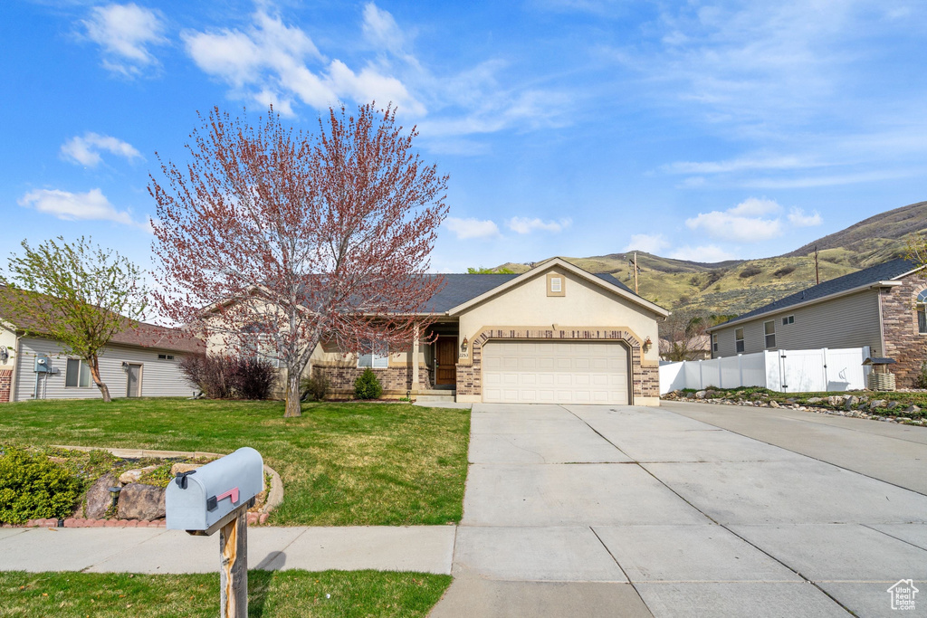 Single story home featuring driveway, an attached garage, a mountain view, fence, and a front yard