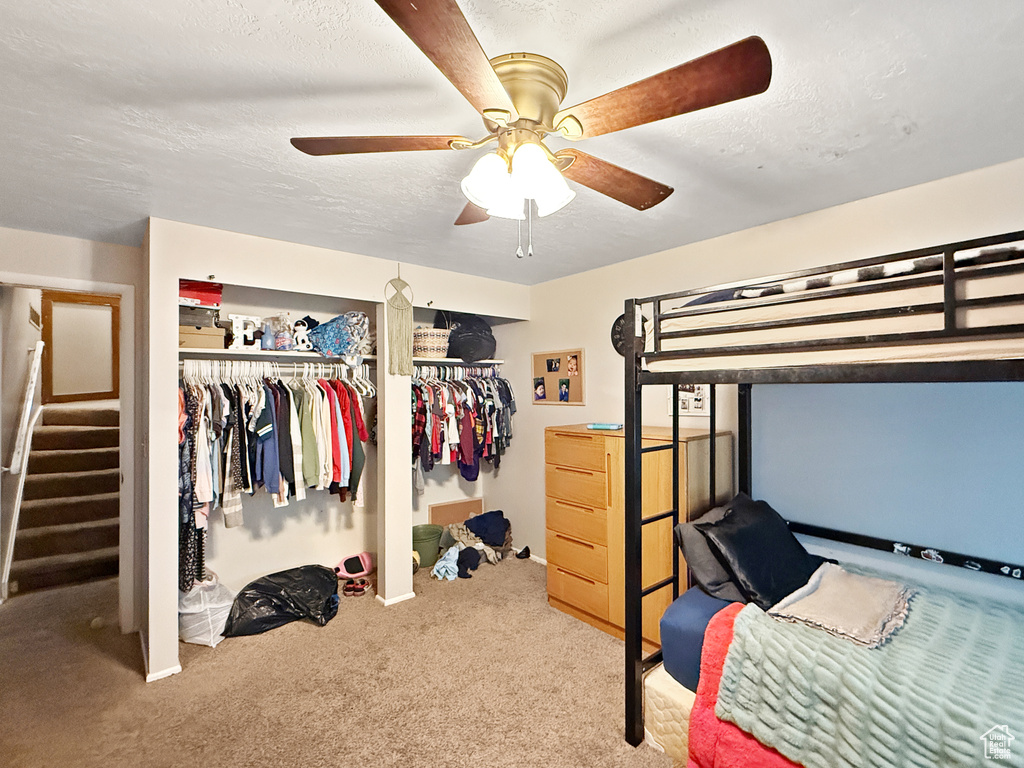 Bedroom with carpet flooring, a ceiling fan, a textured ceiling, and a closet