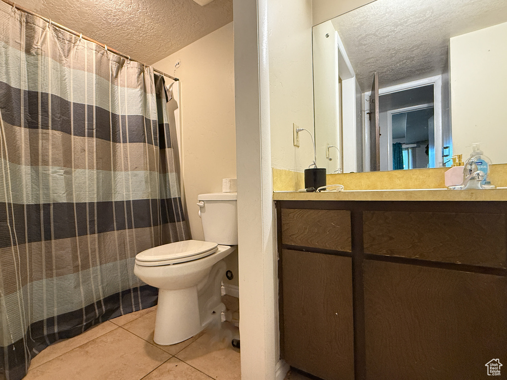 Full bath with vanity, toilet, a textured ceiling, tile patterned floors, and a shower with curtain