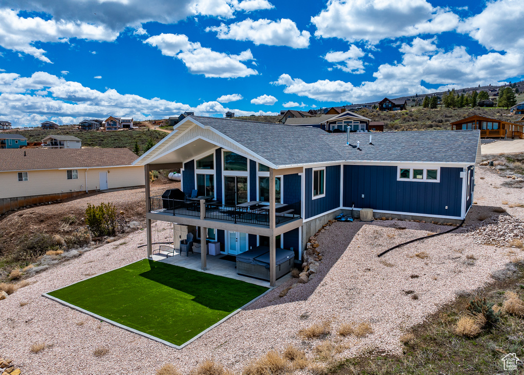 Rear view of property with roof with shingles, a patio, a lawn, and a residential view