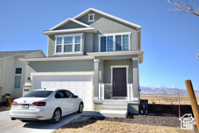 View of front of property with an attached garage, driveway, and stucco siding