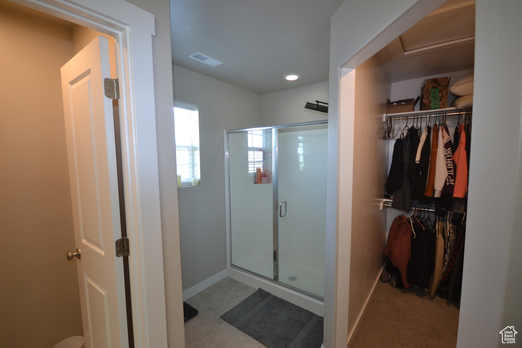 Full bath featuring a stall shower, a walk in closet, baseboards, and recessed lighting