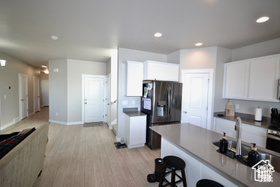 Kitchen with dark countertops, a breakfast bar, light wood-style floors, white cabinetry, and black fridge with ice dispenser