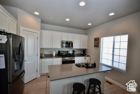 Kitchen featuring a sink, appliances with stainless steel finishes, white cabinets, and a breakfast bar area