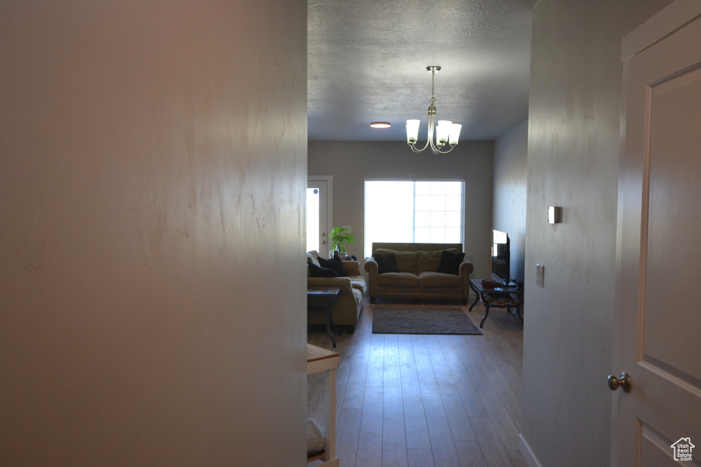 Hall featuring dark wood finished floors, a chandelier, and a textured ceiling