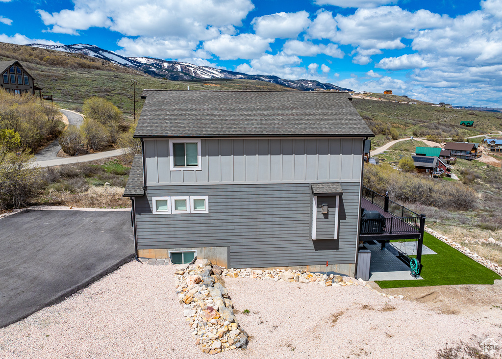 View of home\'s exterior with a shingled roof, board and batten siding, and a deck with mountain view