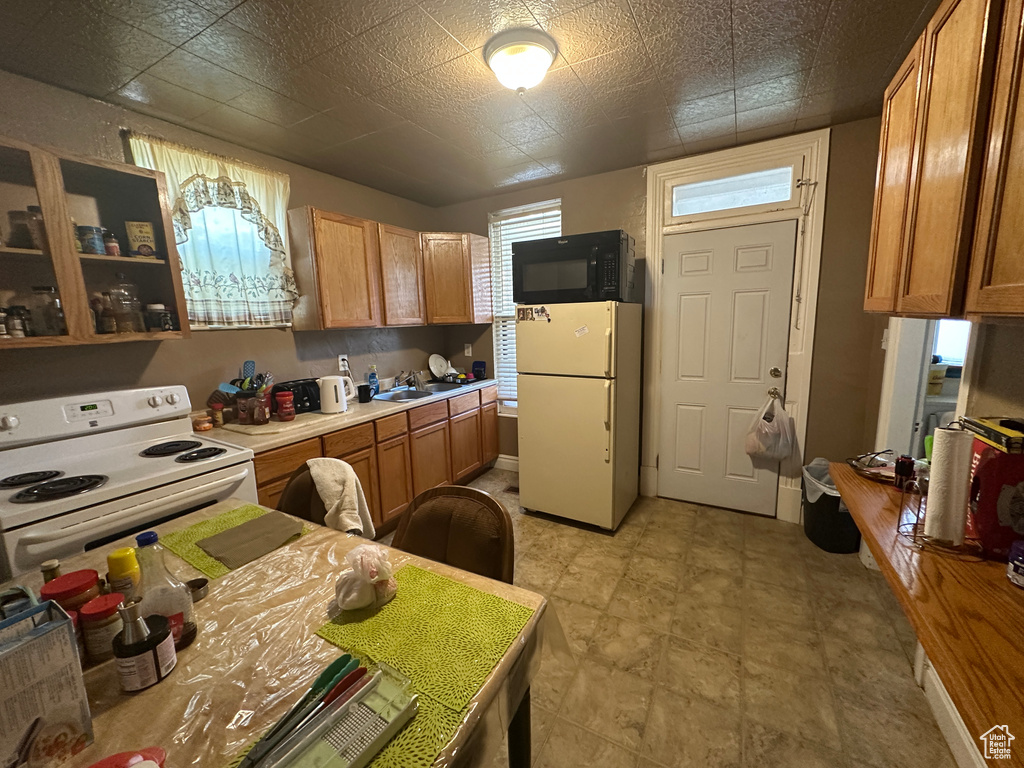 Kitchen with light countertops, a sink, brown cabinets, and white appliances