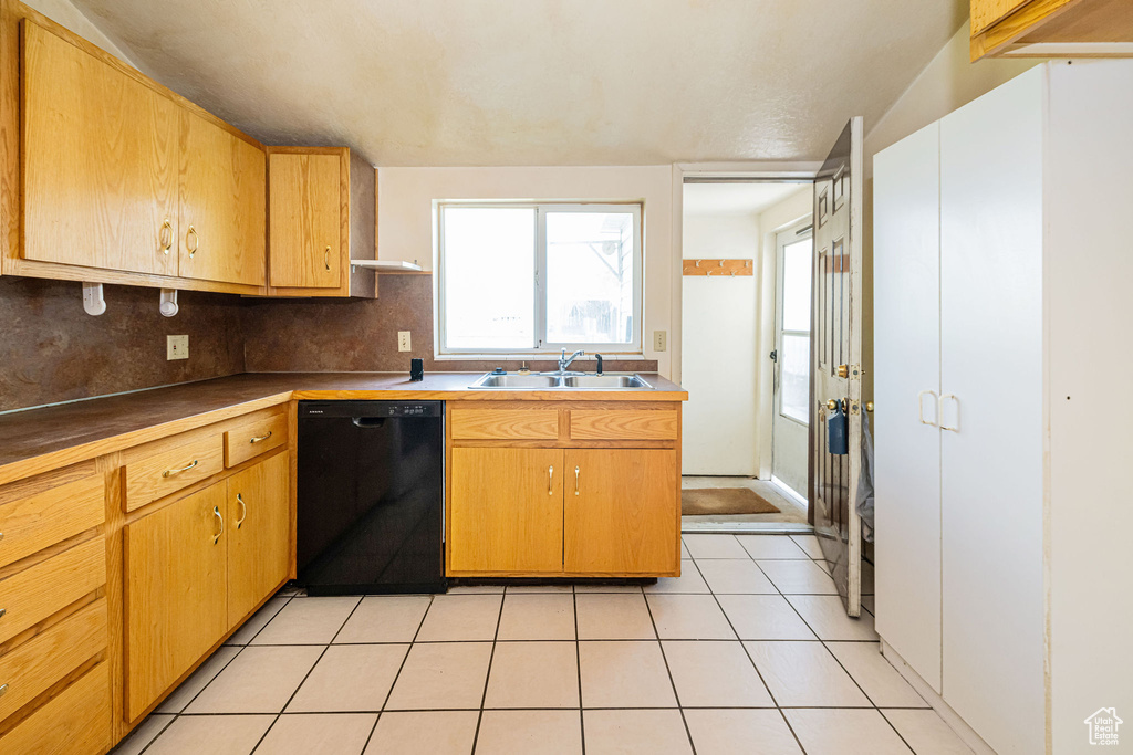 Kitchen featuring a sink, light tile patterned floors, decorative backsplash, and dishwasher