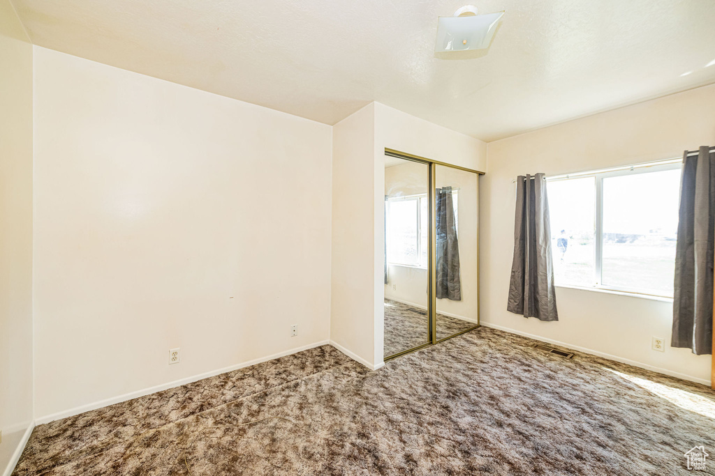 Unfurnished bedroom featuring baseboards, carpet, and a closet
