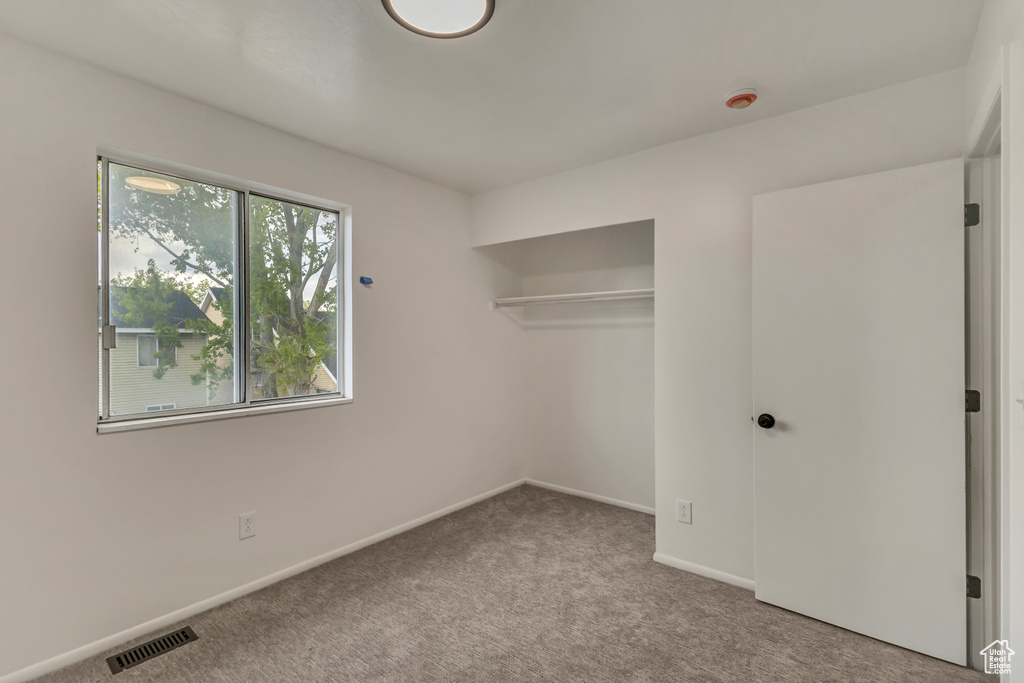 Unfurnished bedroom with carpet floors, baseboards, visible vents, and a closet