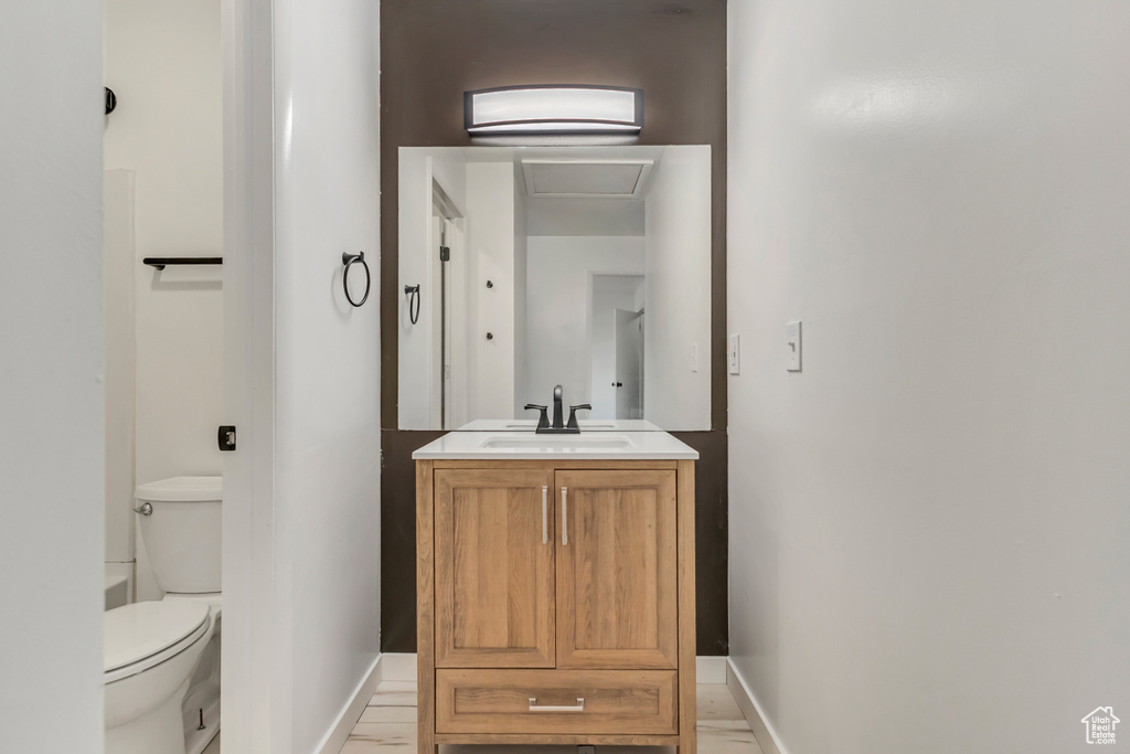 Bathroom featuring toilet, vanity, marble finish floor, and baseboards