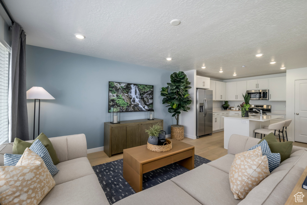 Living area with baseboards, recessed lighting, and light wood finished floors