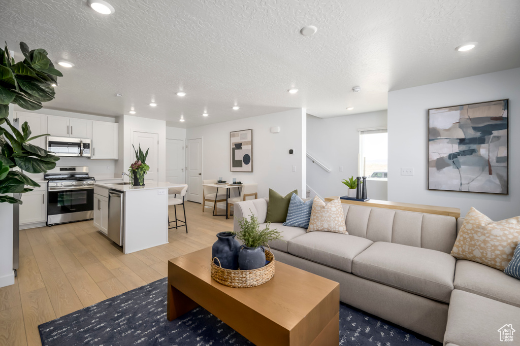 Living area featuring recessed lighting, a textured ceiling, and light wood finished floors