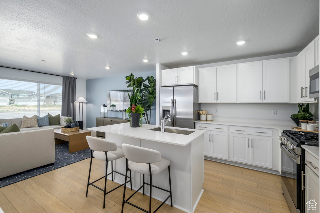 Kitchen with a sink, appliances with stainless steel finishes, light wood-type flooring, and open floor plan