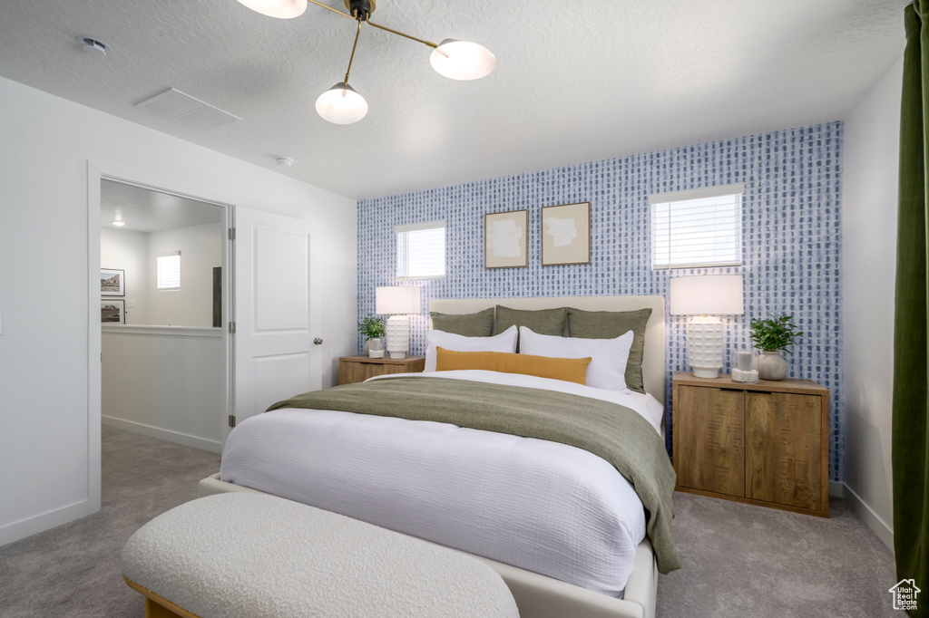 Carpeted bedroom featuring multiple windows, visible vents, baseboards, an accent wall, and wallpapered walls