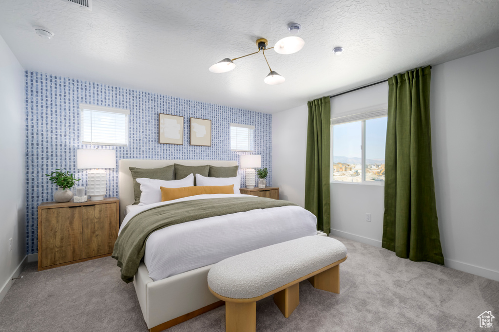 Bedroom featuring a textured ceiling, wallpapered walls, light colored carpet, and baseboards