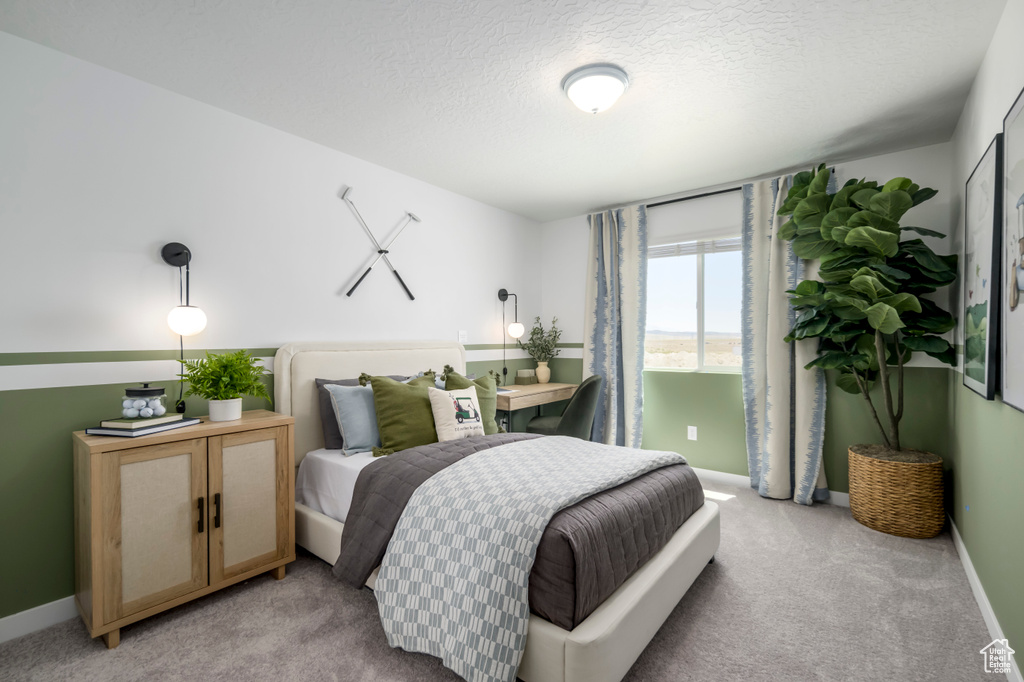 Bedroom with baseboards, a textured ceiling, and light carpet