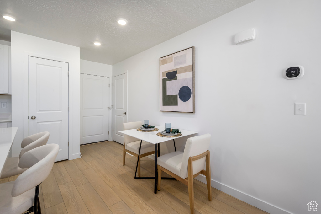 Dining area featuring baseboards, a textured ceiling, light wood finished floors, and recessed lighting