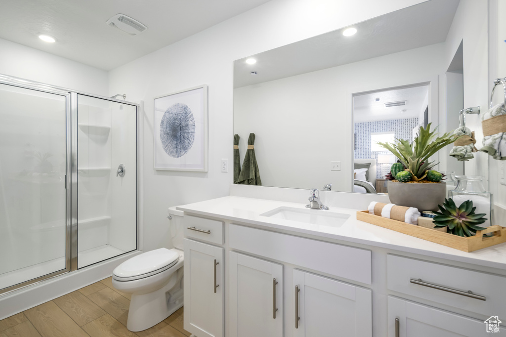 Full bath with a stall shower, wood finished floors, vanity, toilet, and connected bathroom