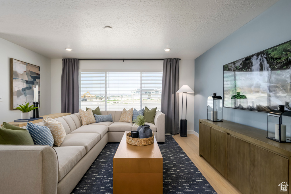 Living area with recessed lighting, light wood-style flooring, and a textured ceiling