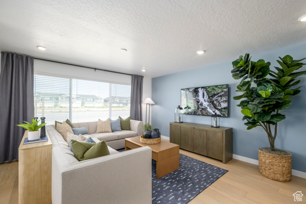 Living area featuring recessed lighting, a textured ceiling, baseboards, and light wood-style floors