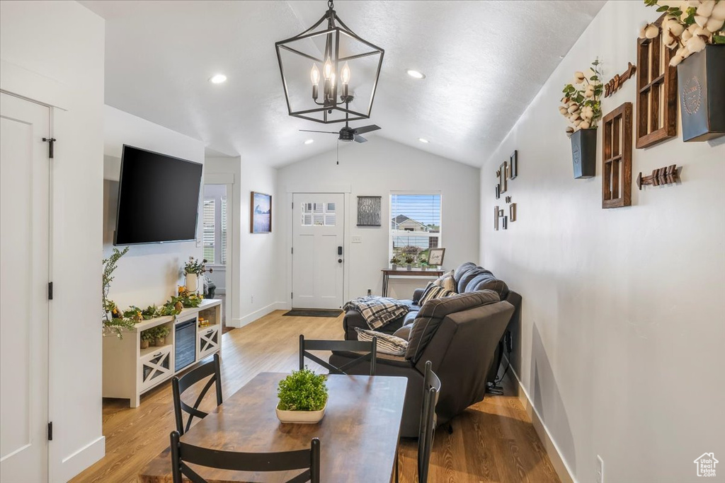 Living area with vaulted ceiling, baseboards, ceiling fan with notable chandelier, light wood-style floors, and recessed lighting