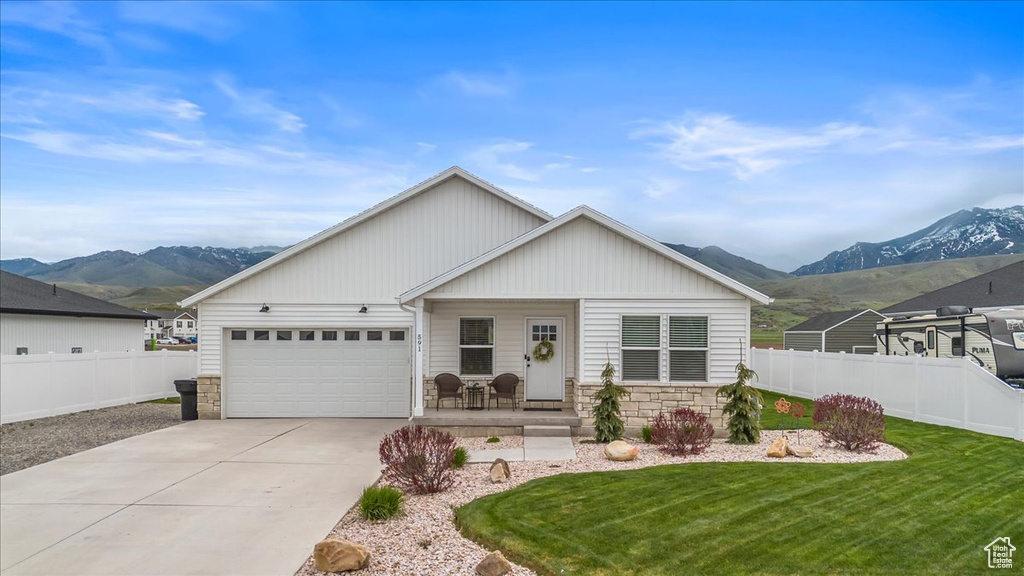 Ranch-style house with a porch, a mountain view, stone siding, and fence
