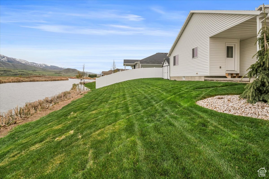 View of yard featuring a water and mountain view and fence