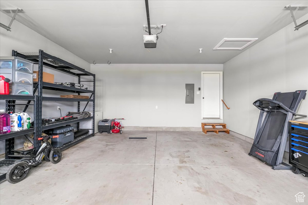 Garage featuring baseboards, a garage door opener, and electric panel