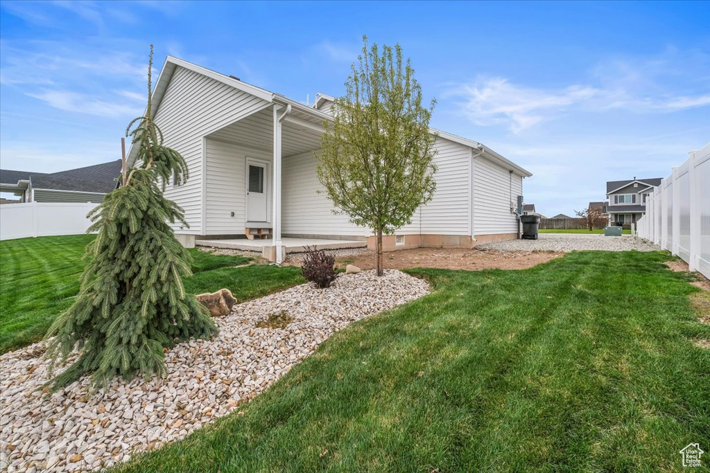 Rear view of property featuring fence and a lawn