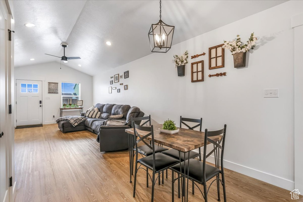 Dining area featuring light wood finished floors, ceiling fan with notable chandelier, recessed lighting, baseboards, and lofted ceiling
