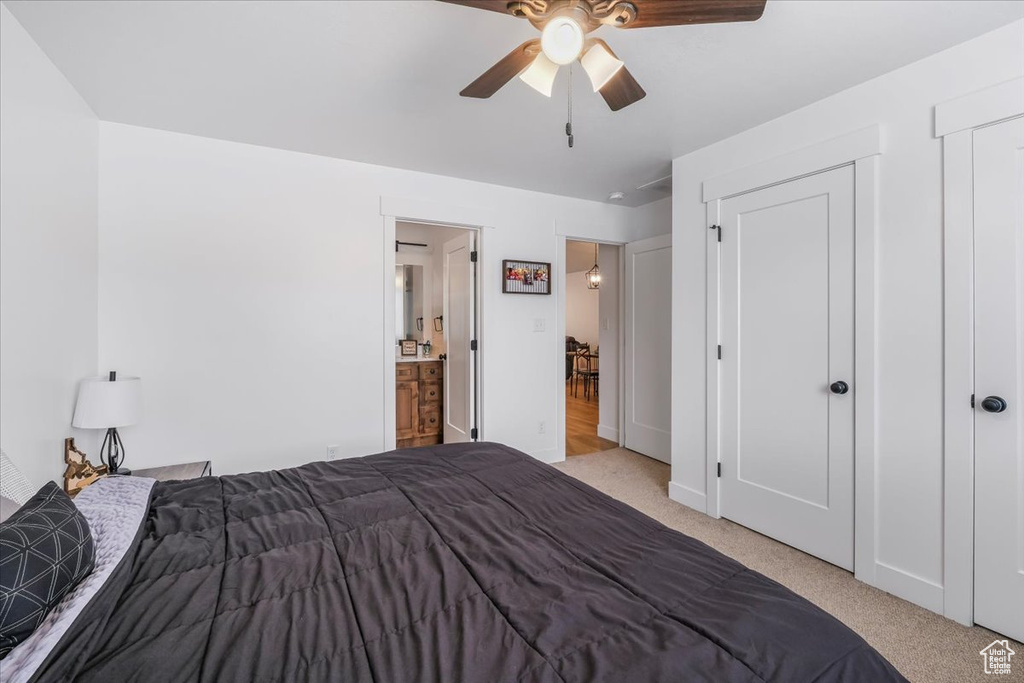 Bedroom featuring ceiling fan, carpet flooring, and ensuite bath