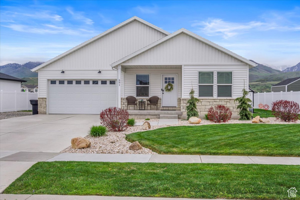 Ranch-style home with fence, covered porch, a mountain view, and stone siding