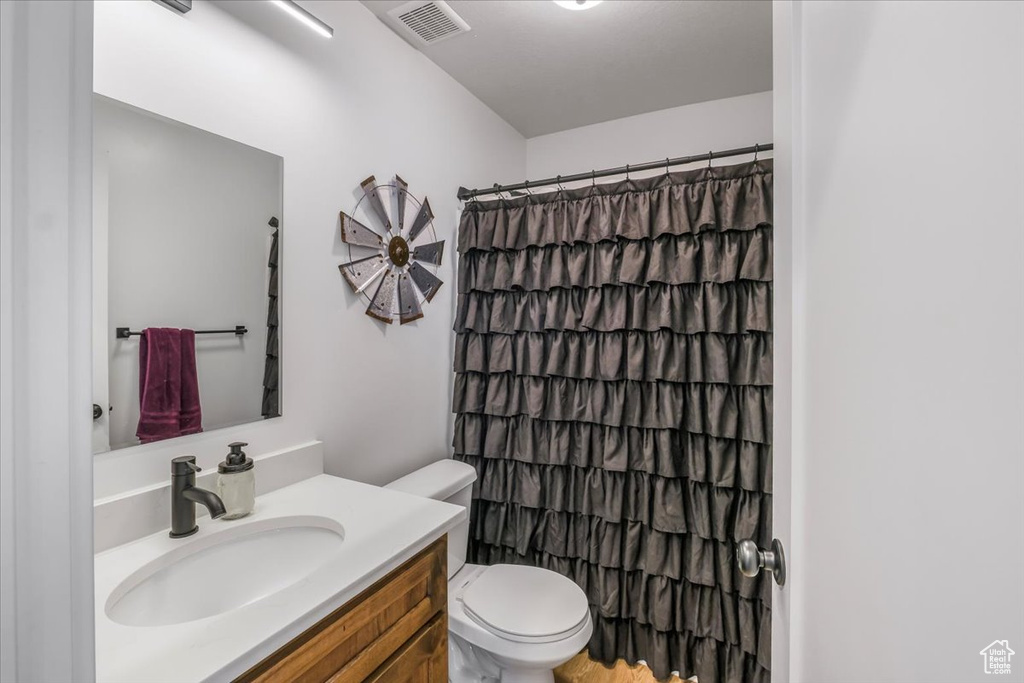 Full bathroom featuring visible vents, a shower with shower curtain, toilet, and vanity