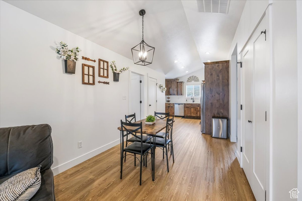Dining room featuring baseboards, vaulted ceiling, light wood finished floors, and visible vents