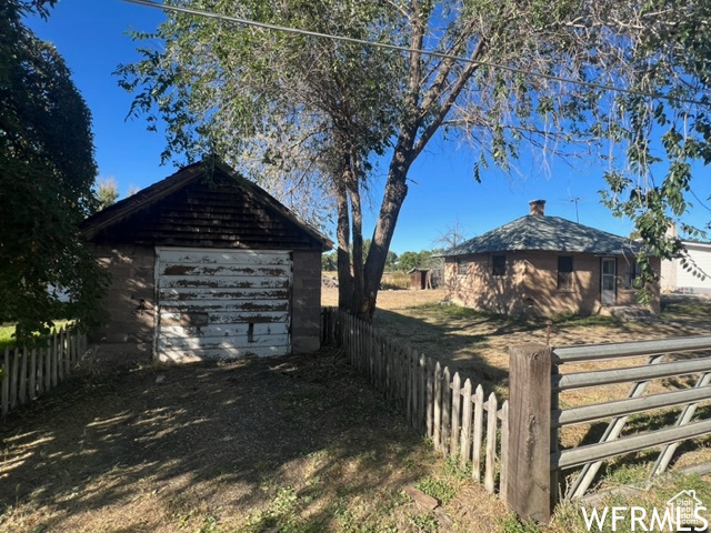 Exterior space with an outdoor structure, a garage, and fence