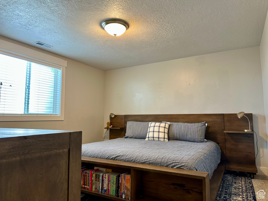 Bedroom with a textured ceiling and visible vents