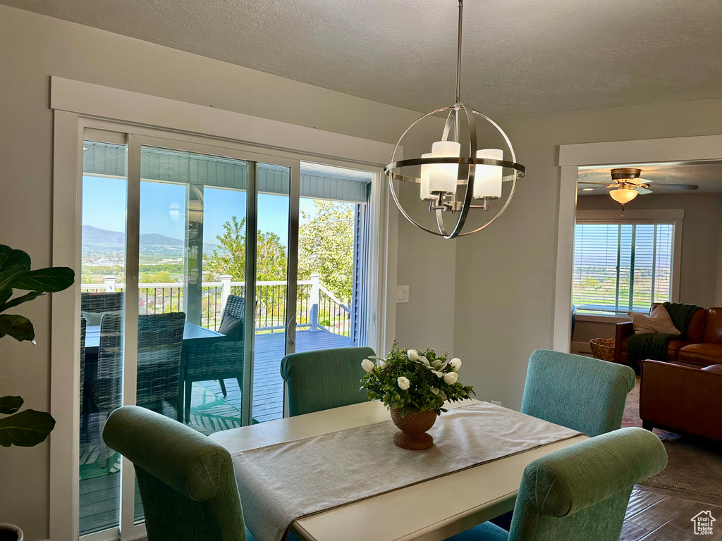Dining room with a textured ceiling, a mountain view, ceiling fan with notable chandelier, and wood finished floors