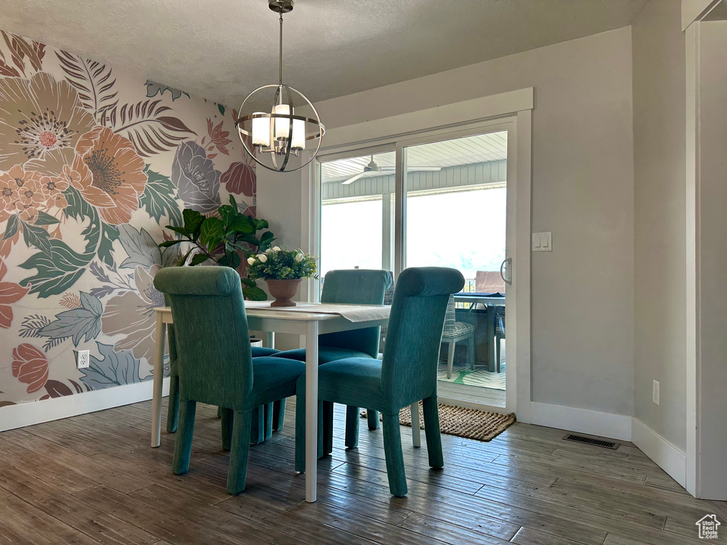 Dining room featuring visible vents, wood finished floors, baseboards, a textured ceiling, and a notable chandelier