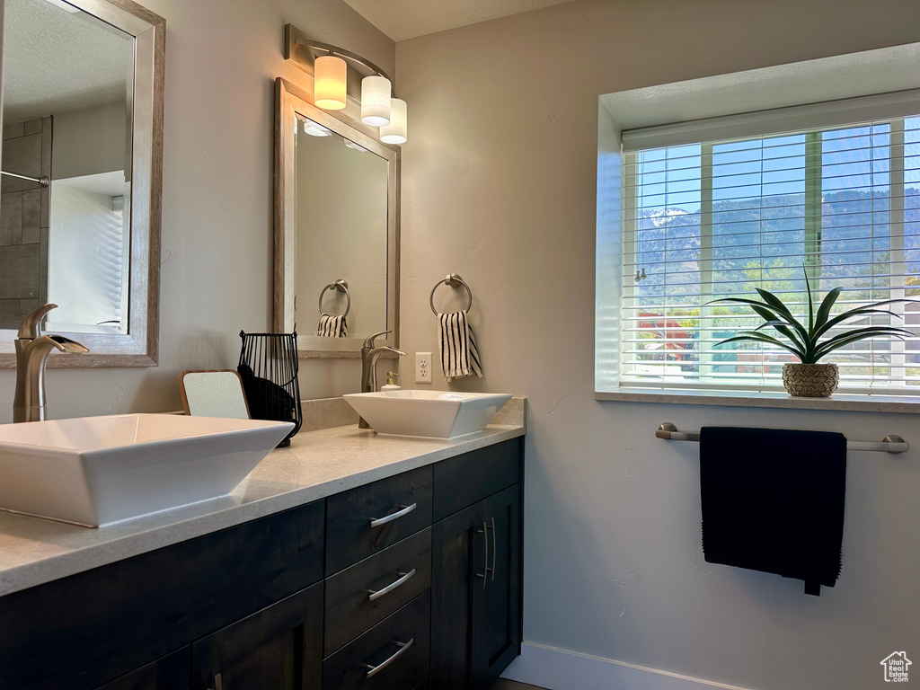Bathroom featuring double vanity, baseboards, and a sink