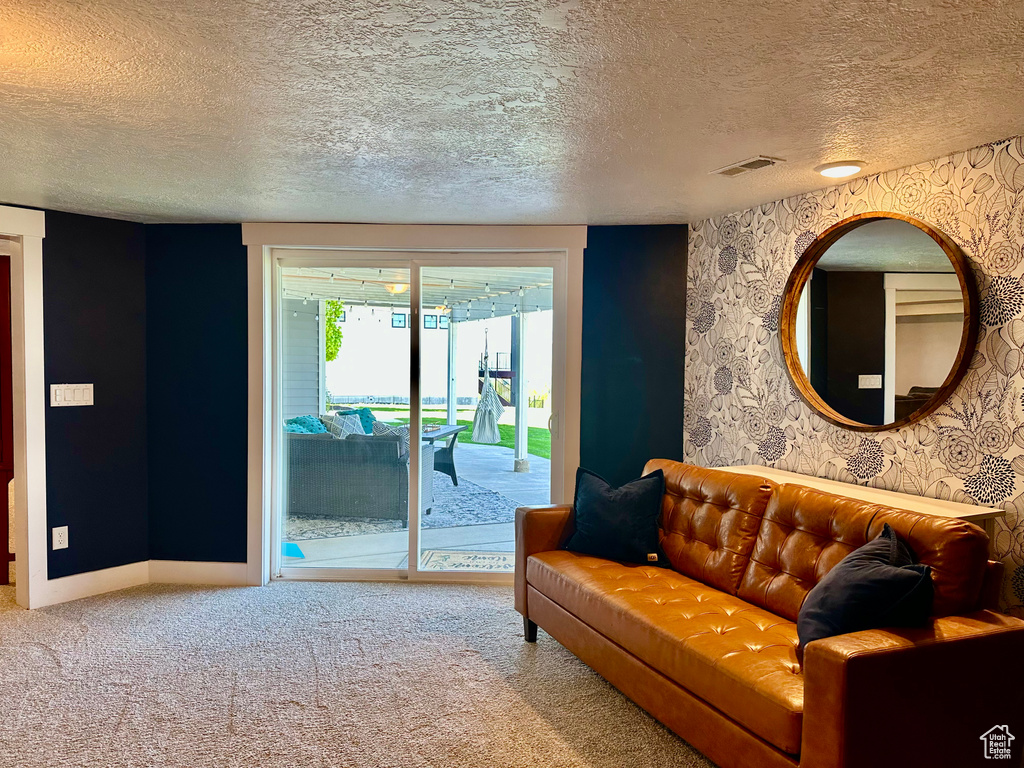 Living room featuring baseboards, carpet, a textured ceiling, and visible vents