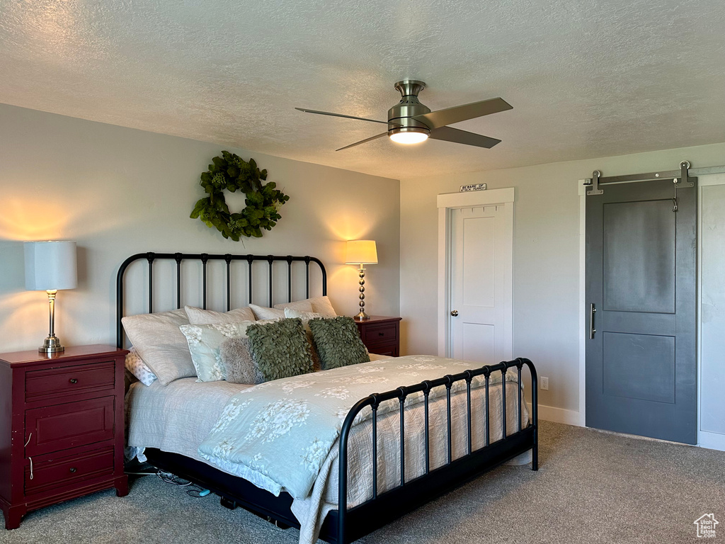 Carpeted bedroom featuring baseboards, a ceiling fan, and a textured ceiling