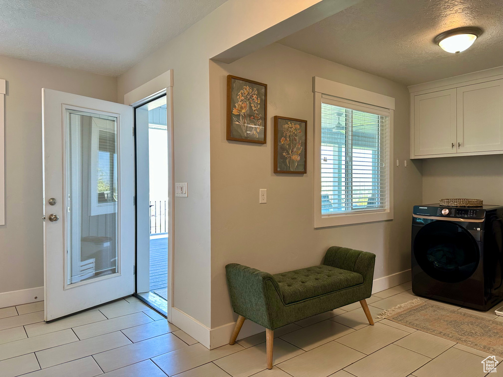 Laundry room with baseboards, a textured ceiling, washer / clothes dryer, and light tile patterned floors