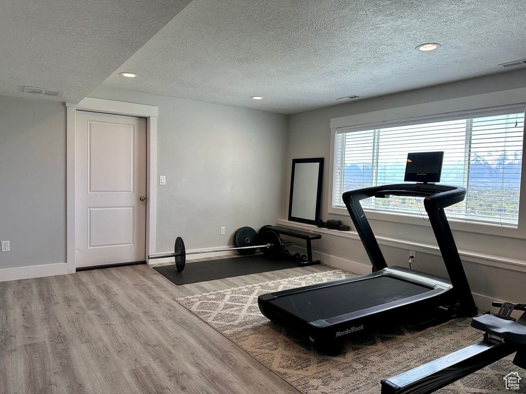 Workout area featuring a textured ceiling and wood finished floors