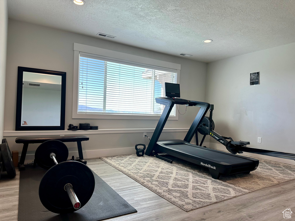 Exercise area featuring visible vents, a textured ceiling, and wood finished floors
