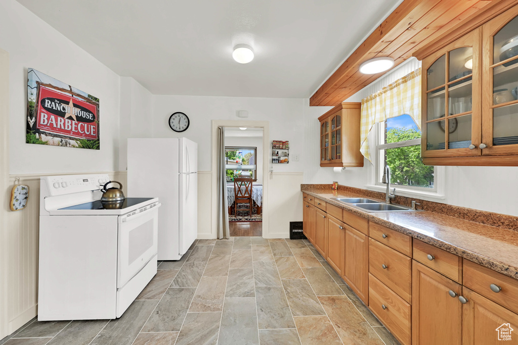 Kitchen featuring a sink, a wealth of natural light, white appliances, and glass insert cabinets
