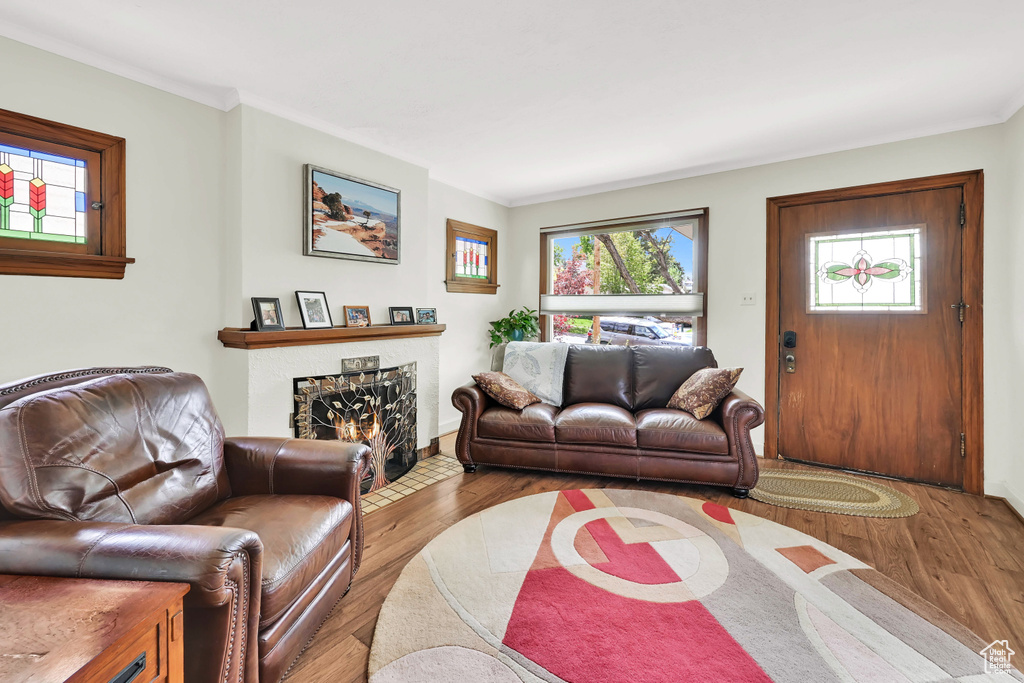 Living area featuring crown molding, a brick fireplace, and wood finished floors