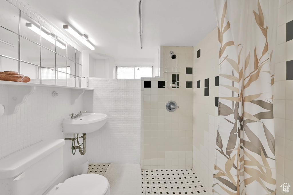 Full bath with a sink, toilet, and tiled shower