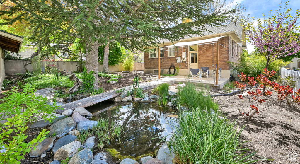 View of yard featuring a patio, a small pond, and a fenced backyard