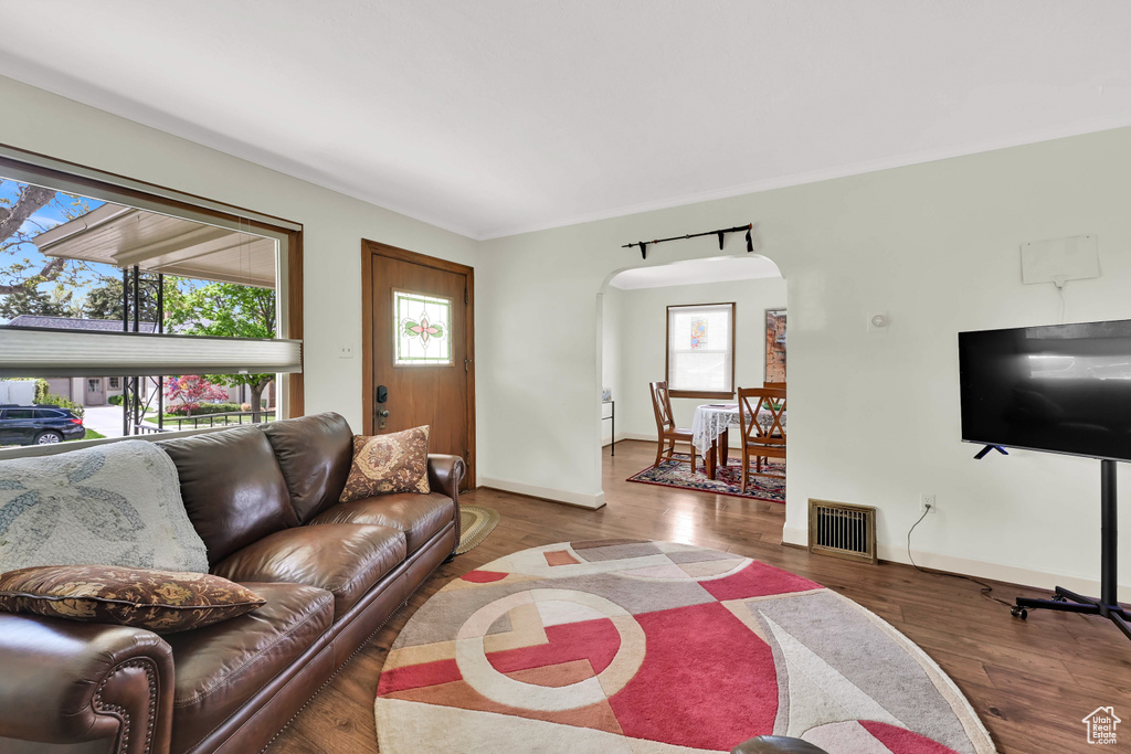 Living room with arched walkways, a wealth of natural light, wood finished floors, and visible vents